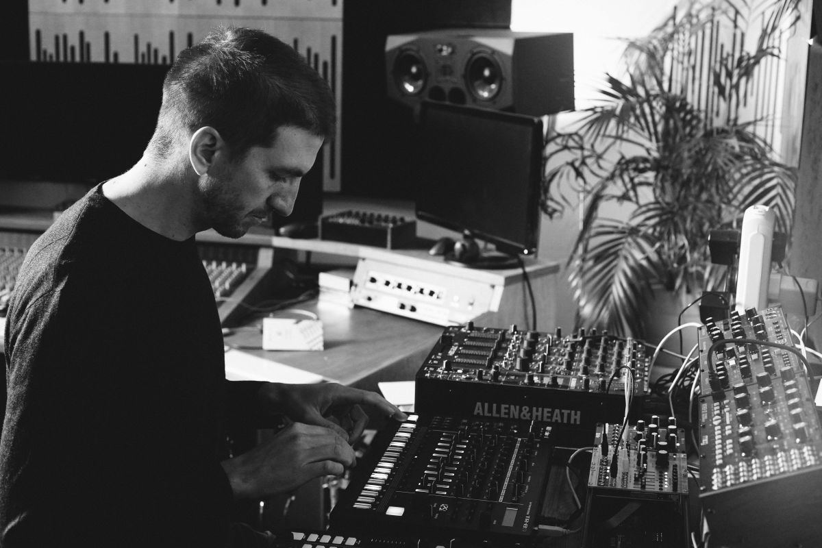 A photo of Alex Banks in his Brighton studio making leftfield bass music, and playing on a drum machine.